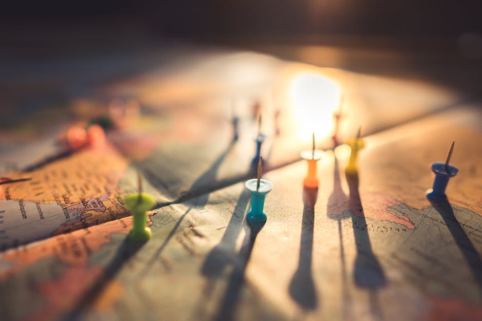 A close-up view of colorful push pins casting shadows on a world map during sunset, highlighting global travel